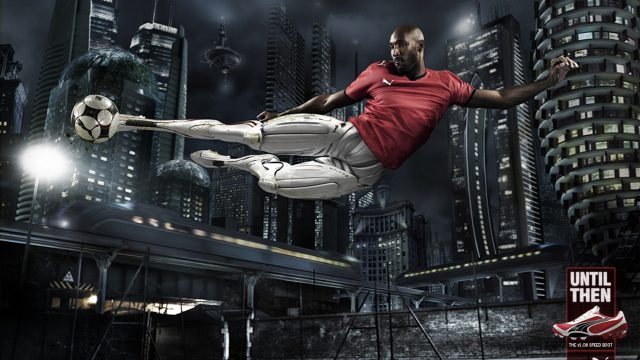 Computer Generated image of a part robot Soccer player scissor kicking a football on a soccer pitch in a futuristic city
